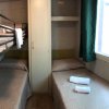 Stanza con letto a castello, letto singolo, armadio e finestra con tenda verde.
