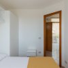 Camera bianca con letto, armadio e porta aperta.