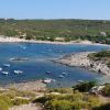 Baia con piccole barche ancorate vicino a una costa rocciosa e colline verdi.