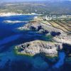 Vista aerea di scogliere rocciose e mare blu intenso.