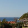 Vista del mare con cielo azzurro tra edifici e alberi.