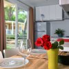 Tavola apparecchiata con fiori rossi e vino in una cucina moderna.