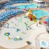 Parco acquatico con piscine, scivoli e ombrelloni blu.