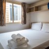 Camera da letto semplice con letto matrimoniale, lenzuola bianche e finestre con tende.