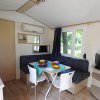 Interno di un bungalow con tavolo da pranzo, cucina e divano; finestra con vista sul verde.