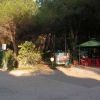 Strada sterrata vicino a un'area alberata con sedie rosse sotto un gazebo verde.
