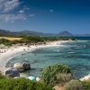 Spiaggia con acqua cristallina e montagne sullo sfondo.