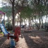 Un parco giochi con scivolo e giocattoli a molla, immerso in un'area boschiva.