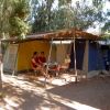Tenda da campeggio tra gli alberi con tre persone sedute.