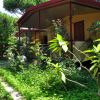 Villette gialle con tetto rosso, avvolte da fiori e vegetazione.
