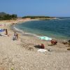 Una spiaggia di ciottoli con persone e ombrelloni vicino al mare.