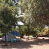 Area camping con tenda, amaca e alberi ombrosi.