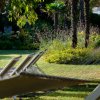 Hammock e sedie a sdraio su un prato curato con fiori e palme.