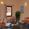 Sala con tavoli, sedie, quadri alle pareti e finestre che danno su una piscina.