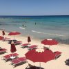 Spiaggia con ombrelloni rossi e mare limpido.