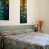 Letto matrimoniale con copriletto multicolore e quadri floreali alle pareti.
