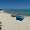Spiaggia attrezzata con lettini e pedalò colorati.