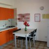 Cucina con mobili arancioni e tavolo bianco.