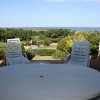 Vista mare da un patio con sedie e tavolo bianchi.