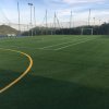 Campo da calcio in erba sintetica con linee gialle.