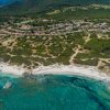 Vista aerea di un villaggio costiero con spiaggia e mare turchese.