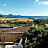 Vista su mare e montagne da una terrazza con sedie bianche.