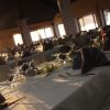 Tavoli apparecchiati per cena in una sala illuminata dalla luce del tramonto.