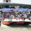 Spiaggia con ombrelloni blu, sdraio e pedalò rossi.