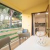 Balcone con tavolo bianco e vista su alberi, accesso a cucina.