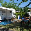 Camper parcheggiato accanto a un'area picnic con tavoli e sedie all'aperto.