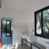 Un bagno con due lavandini bianchi e piastrelle quadrate, finestra grande a destra.