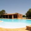 Piscina all'aperto con terrazza in mattoni e casetta in pietra sullo sfondo.